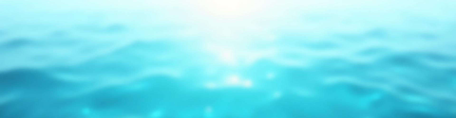 Riak lembut di permukaan laut yang tenang, mencerminkan langit biru